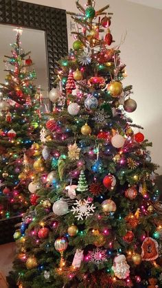 a brightly colored christmas tree in a living room with ornaments on the top and bottom