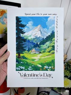 someone holding up a valentine's day card with a mountain scene in the background