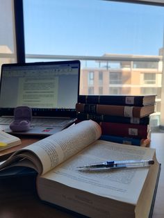 an open book sitting on top of a desk next to a laptop computer and pen