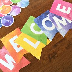 colorful paper cut out to spell out the word welcome on a table with stickers