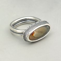 This beautiful handcrafted sterling silver ring offers a small imperial jasper stone with earthy colors. It has a nice comfort fit due to the square shank. Great for everyday wear and perfect for gift giving. Materials: sterling silver and imperial jasper Finish: ring have been given a patina Sizes: size 7 Dimensions: stone setting is 7/8 x 0.5 inches and the ring shank is 5 mm thick Care: Avoid getting the ring wet to preserve the patina and prevent damaging the stone. Shipping: this jasper rin Handmade Jasper Rings For Gift, Unique Jasper Rings For Gift, Vintage Jasper Jewelry For Gifts, Handmade Silver Jasper Rings, Earthy Jasper Hand-strung Jewelry, Handcrafted Silver Jewelry, Jasper Ring, Metalwork Jewelry, Metalsmithing Jewelry