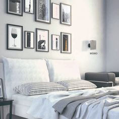 a white bed sitting in a bedroom next to a window with pictures on the wall