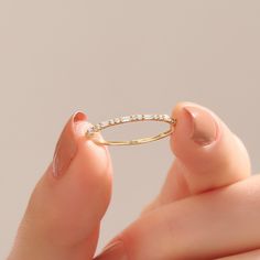 a close up of a person holding a gold ring with small diamonds on the side