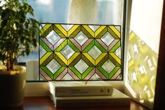 a stained glass window sitting on top of a wooden table next to a potted plant