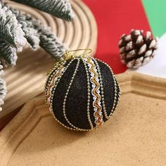 a black ornament sitting on top of a table next to some pine cones