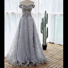 a wedding dress on display in front of a window with cacti behind it