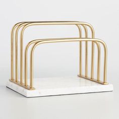 three white marble and gold - plated metal stands on a white surface, with one standing upright