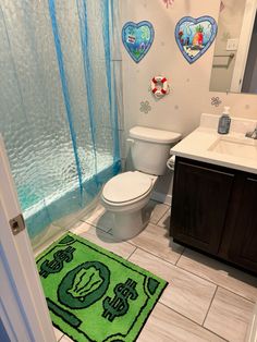 a bathroom with a green rug on the floor next to a toilet and shower curtain