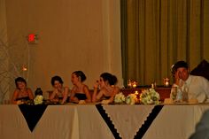 a group of people sitting at a table in front of candles and flower centerpieces