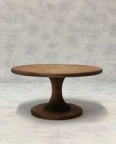 a round wooden table on a plain surface with no one around it or in the background