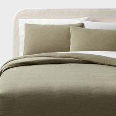 an unmade bed with beige sheets and pillows