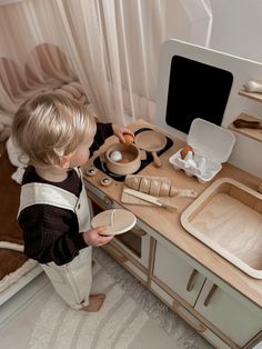 a little boy that is standing in front of a desk with some food on it