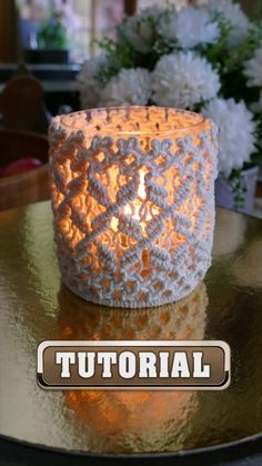 a white crocheted candle holder sitting on top of a table next to flowers