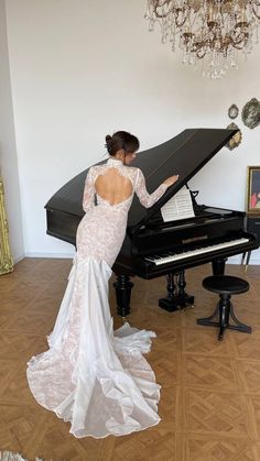 a woman in a white dress is playing the piano with her back to the camera