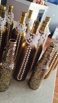 there are many bottles with pearls in them on the counter top and one is gold