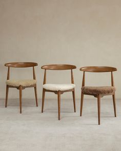 three wooden chairs sitting next to each other on top of a white carpeted floor