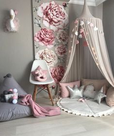 a child's bedroom decorated in pink and grey with flowers on the wall behind it