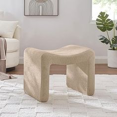 a living room with a white rug and a beige bench in front of a window