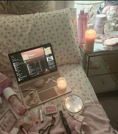 an open laptop computer sitting on top of a bed next to candles and other items