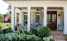 a white house with pillars and columns on the front porch is surrounded by greenery