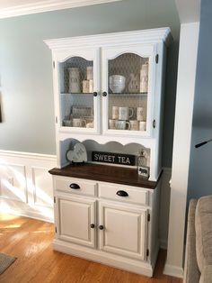 a white china cabinet with glass doors and drawers