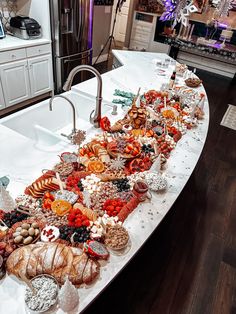 a long table filled with lots of food on top of a kitchen counter next to a sink