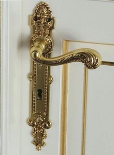 an ornate gold door handle on a white door