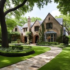 a large brick house surrounded by lush green grass and trees in the front yard, with a stone walkway leading to it