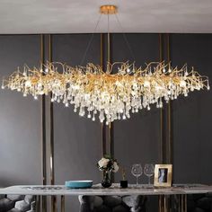 an elegant chandelier hangs over a dining room table with chairs and vases