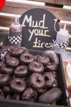 there is a tray full of chocolate donuts and a sign that says mud your tires