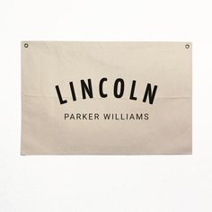 a lincoln sign hanging from the side of a building in front of a white wall