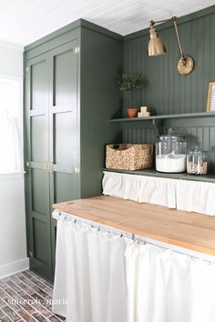 a kitchen with green walls and white curtains