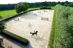 an aerial view of a horse and rider riding on the sand in a fenced area