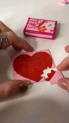 someone is cutting out a heart from a piece of paper