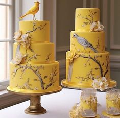 three tiered yellow wedding cake with birds on top and cherry blossoms around the edges