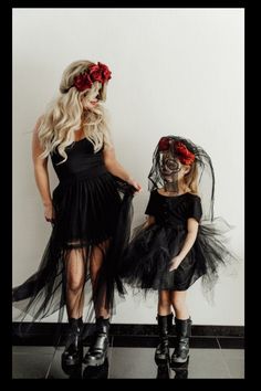 two girls dressed up in black and one is wearing a skeleton mask with flowers on her head