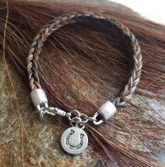 a close up of a bracelet on a rock with a horse shoe charm attached to it