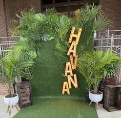 an outdoor area with fake grass, plants and wooden letters that spell out the word hawaiian