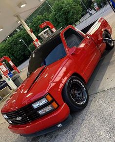 a red chevrolet camaro is parked in front of a gas station with its hood up