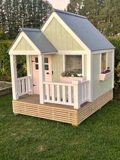 a small wooden house sitting on top of a lush green field