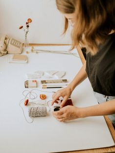 a woman is making necklaces on a table