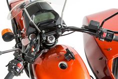 an orange motorcycle with a digital clock on the handlebars