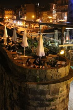 an outdoor restaurant with tables and umbrellas lit up at night, overlooking the water