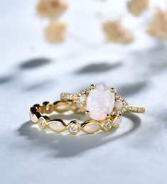 an opal and diamond ring is shown on a white surface with flowers in the background