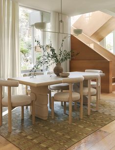 a dining room table with chairs and a vase filled with flowers on top of it