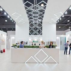 people are standing at the reception desk in an office building with white walls and ceilings