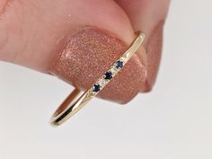 a person's hand holding a gold ring with blue and white stones on it