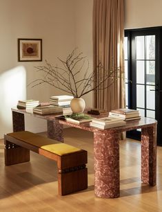 a table with books and a vase sitting on top of it next to a bench