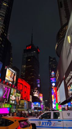 a busy city street at night with lots of neon signs and cars driving on it