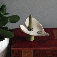 a small white dish with two rings on it sitting next to a potted plant